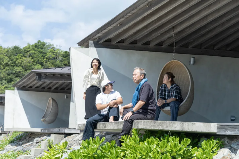 海辺の建築の前に集まるスタッフ