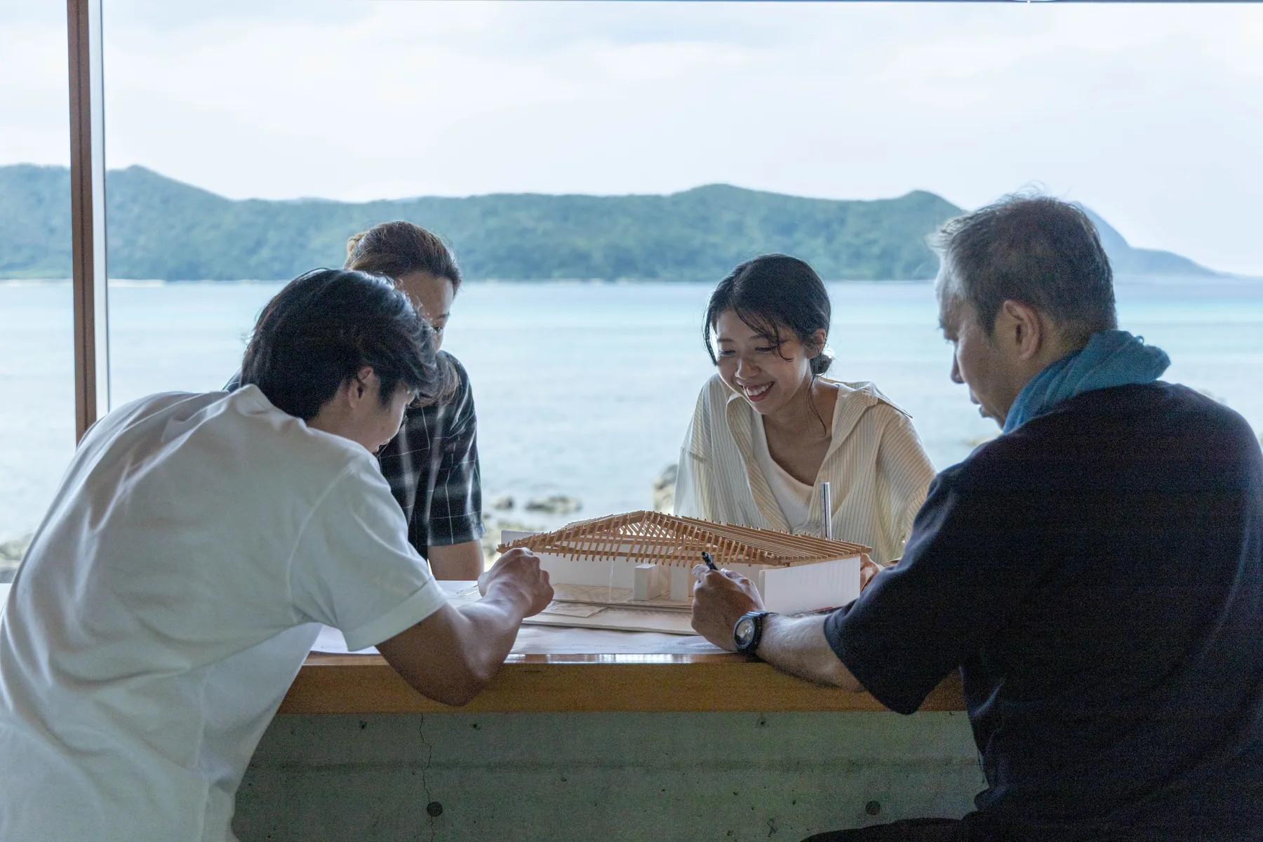 模型を囲み、海を背景に話し合う天工人のスタッフ